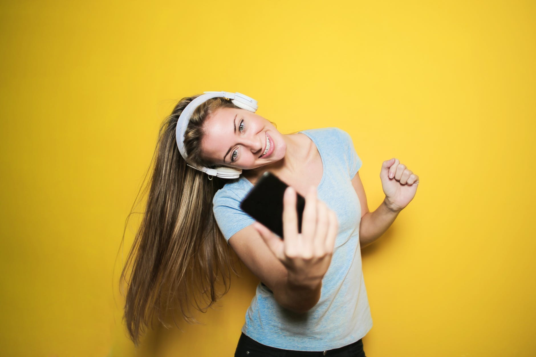 satisfied woman taking selfie on smartphone in studio