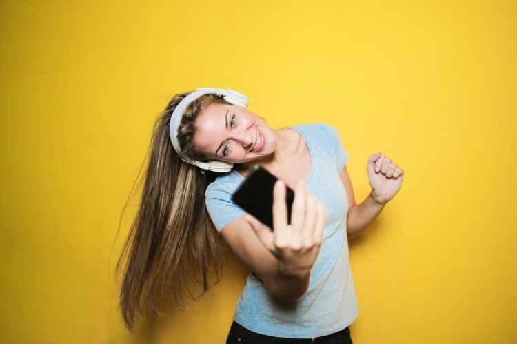 satisfied woman taking selfie on smartphone in studio
